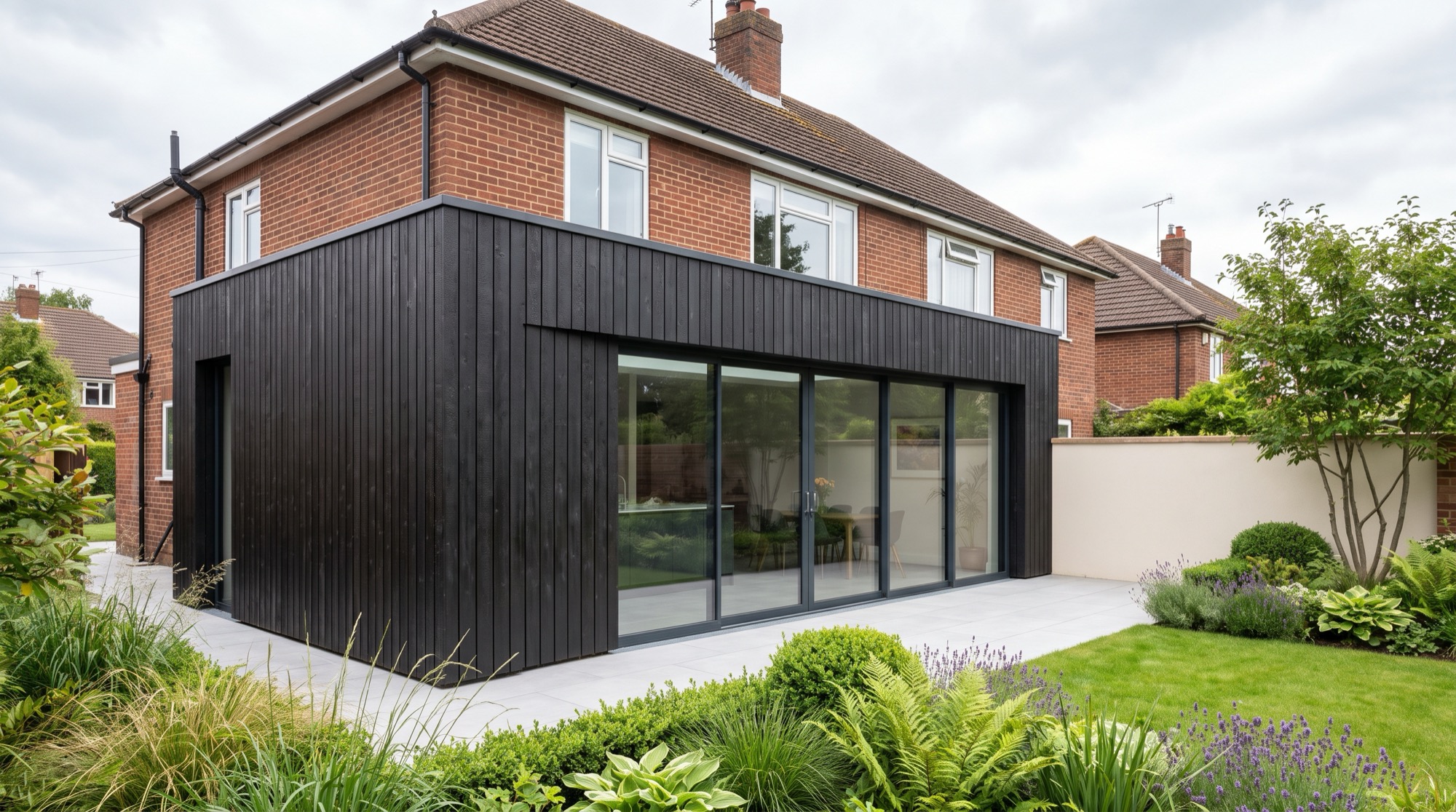 A Nordu rear extension in charred black timber cladding, with full height
                sliding glazing opening onto a garden.